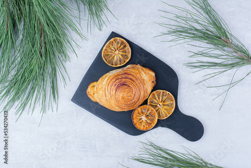 Delicious pastry with dried orange slices on black board