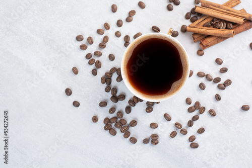 Cup of coffee, cinnamons and coffee beans on gray surface