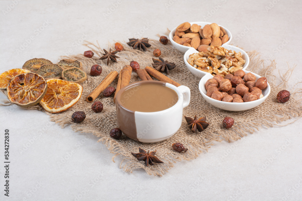 A cup of coffee with dried oranges and nuts on marble background A cup of coffee with dried oranges and nuts on marble background