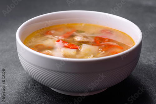 Closeup of a bowl of chicken noodle and vegetable soup on a concrete table