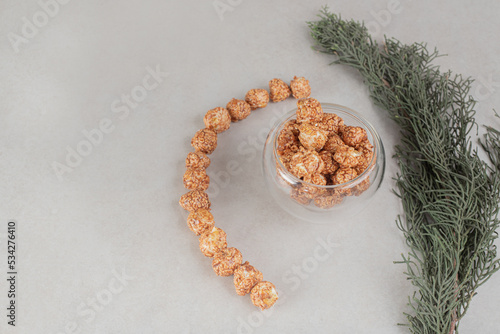 Tree branch next to decoratively aligned mass of popcorn candy on marble background