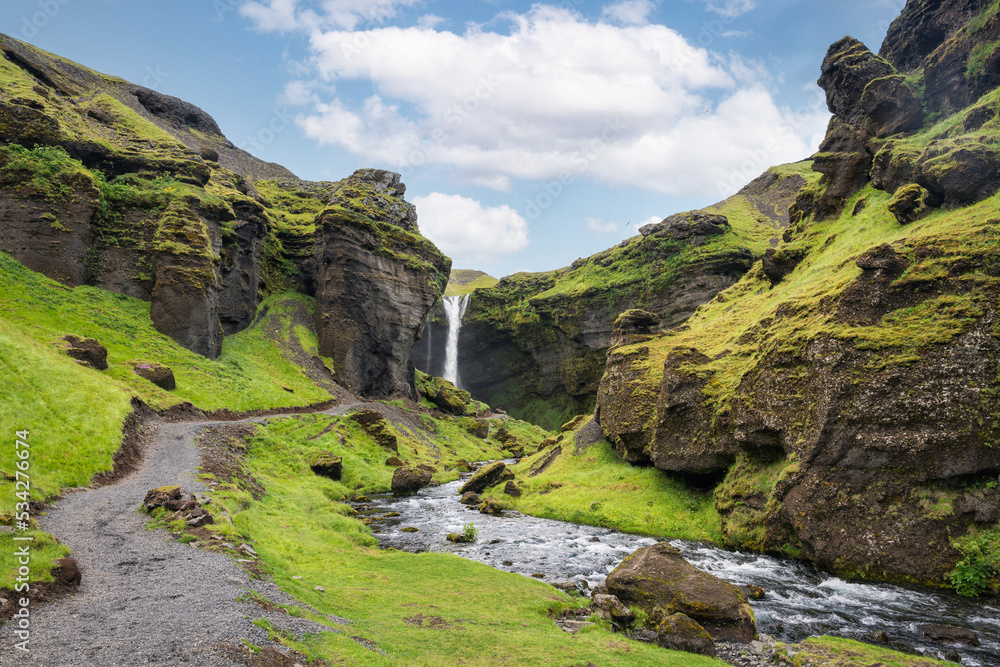 Majestic landscape of Kvernufoss waterfall flowing through the green valley in sunny day on summer at Iceland