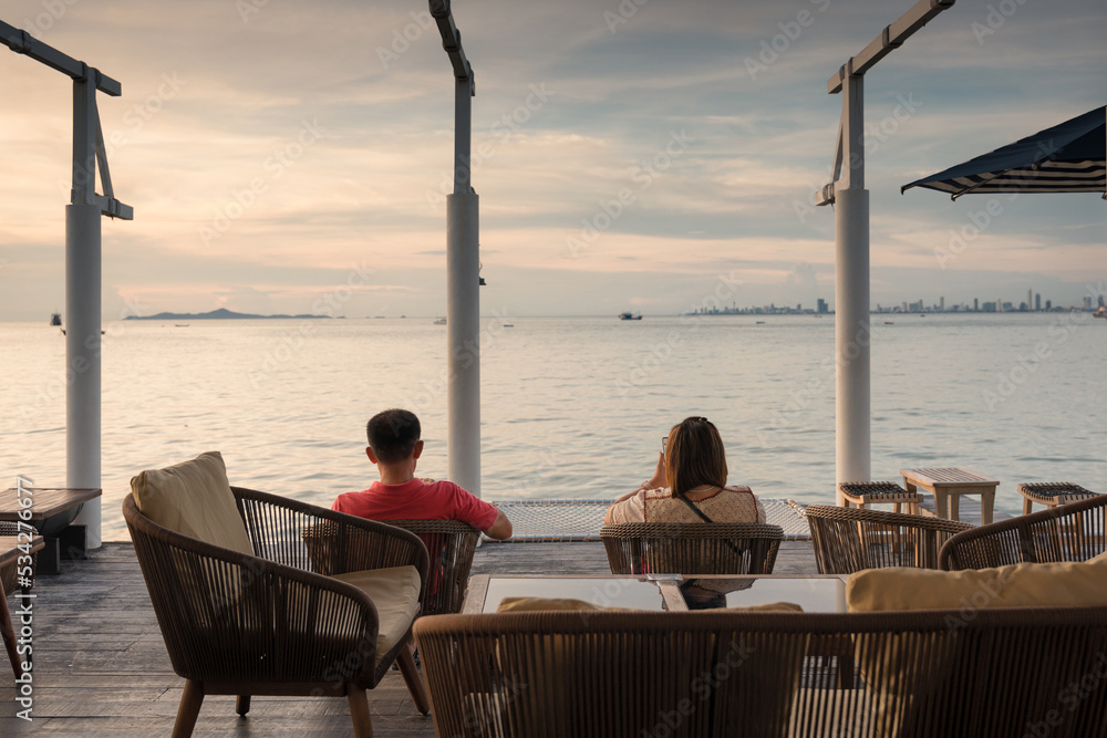 Retired adult couple sitting outdoor and relaxing on terrace by tropical sea