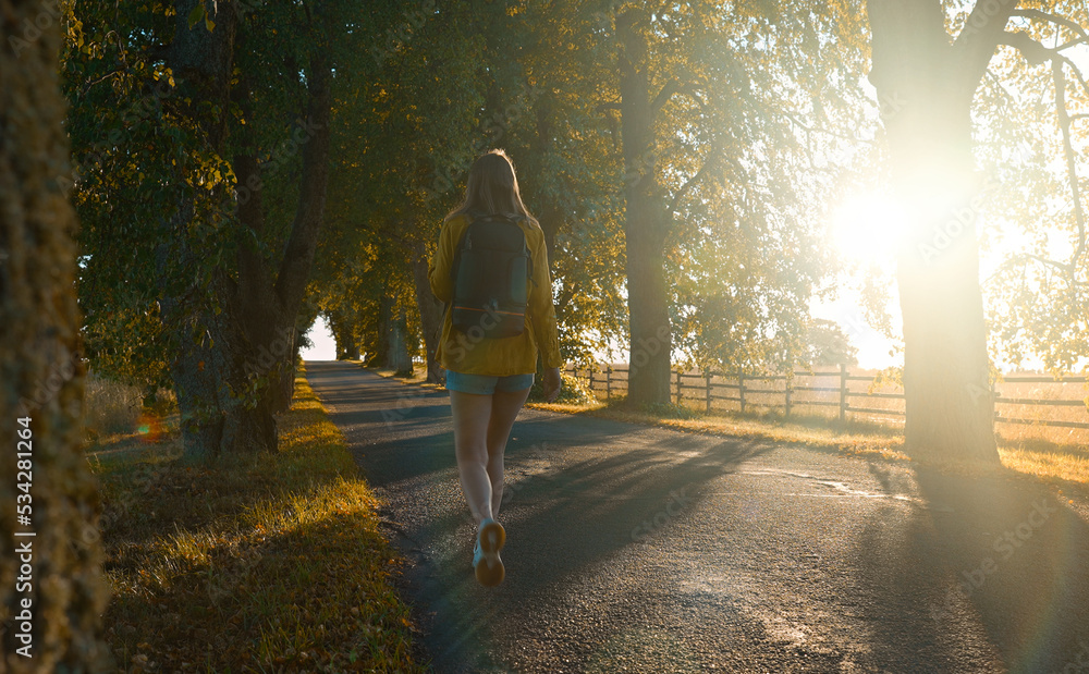 Woman tourist with backpack walking in the countryside. Rear view. Woman tourist with backpack walking in the countryside. Rear view.