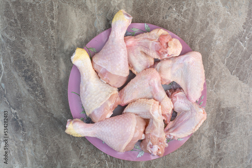 Uncooked chicken legs on pink plate