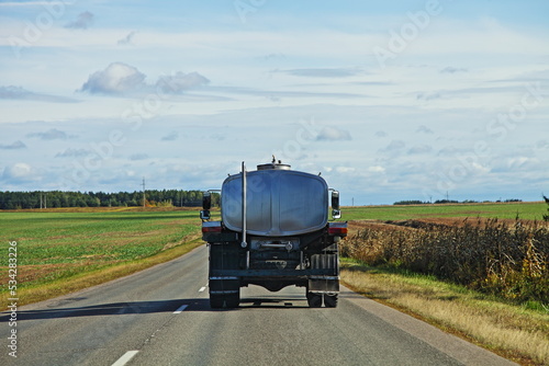 Milk barrel truck drive on countryside road . Liquid food goods delivery