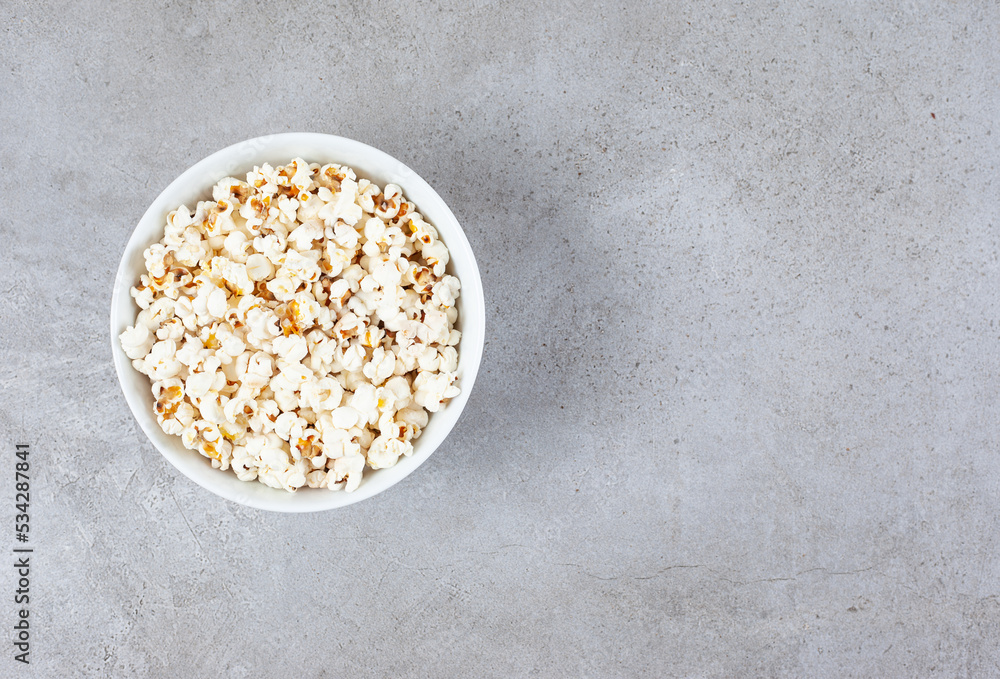 A bowl full of crunchy popcorn on marble background A bowl full of crunchy popcorn on marble background