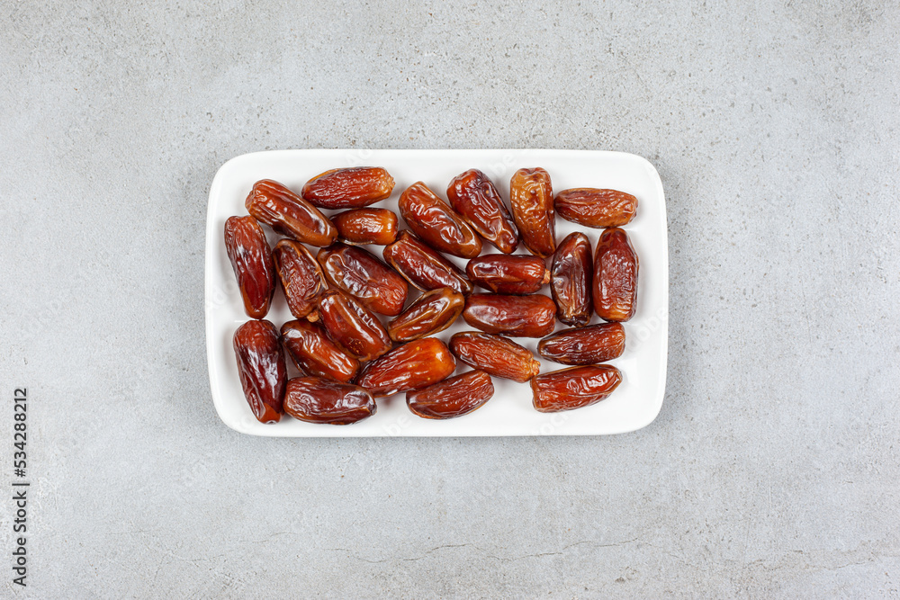 Square plate full of dates on marble background Square plate full of dates on marble background