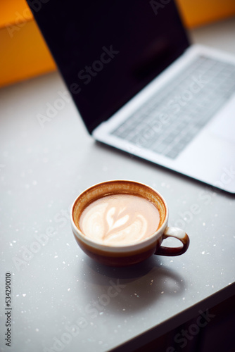 Close Up Of Coffee Next To Laptop In Window Of Coffee Shop