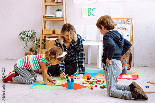 Female psychiatrist, pedagogue playing and learning to imagine with children, creative painting in development center 