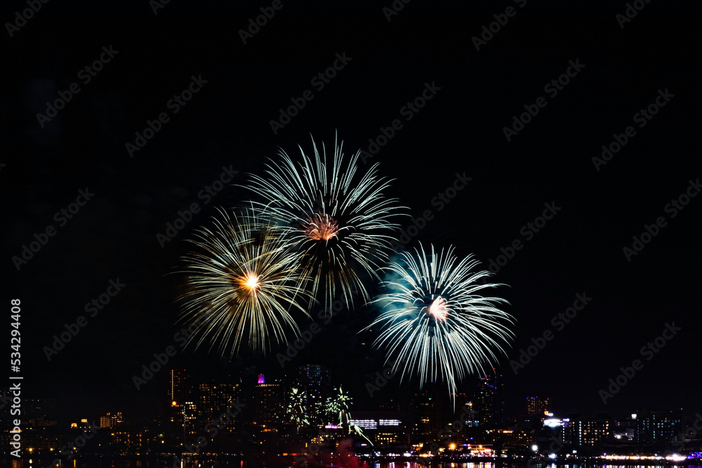 fireworks exploding in the night sky over a city. The fireworks are green, blue, and white. fireworks exploding in the night sky over a city. The fireworks are green, blue, and white.
