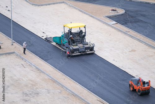 Asphalt paver laying asphalt road at construction site, car park reconstruction