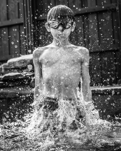 Foto young boy wearing goggles swimming in the backyard pool - fast shutter speed and