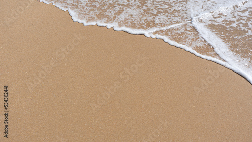 foam of the sea waves breaking on the beach shore