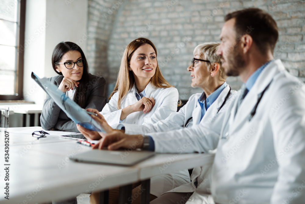 Group of doctors analyzing medical scan with businesswoman in the hospital Group of doctors analyzing medical scan with businesswoman in the hospital