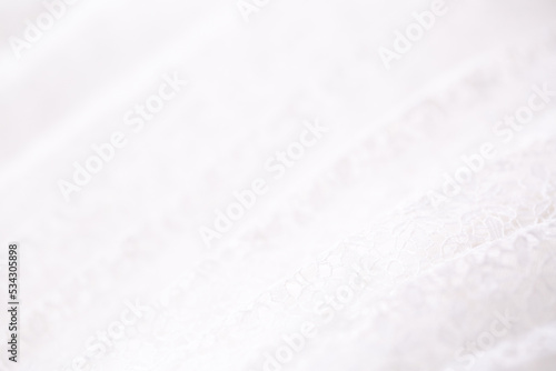 White fabric pleated with lace as a background. Lightweight summer clothing material, patterned texture. Wedding Dress.