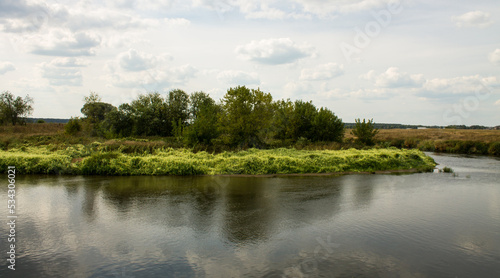 Beautiful landscape - the Klyazma river between the banks with green grass and trees against a cloudy sky on a summer day in the Moscow region photo