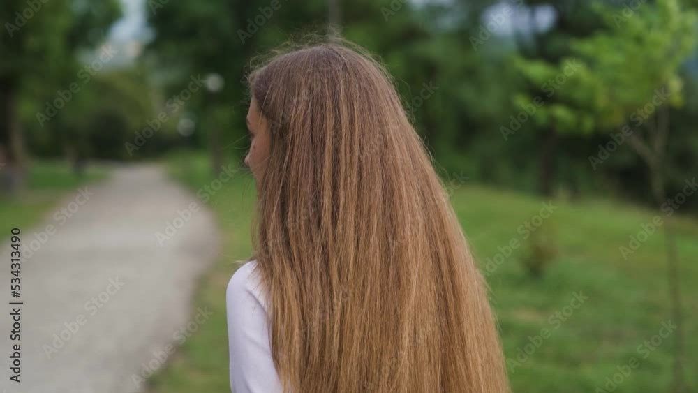 The young woman walk, turn and smile in the city park background. Slow motion. The young woman walk, turn and smile in the city park background. Slow motion.