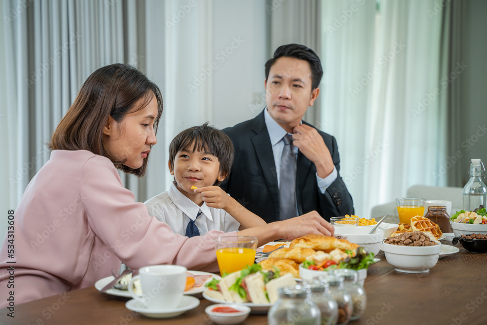 Portrait of happy parents feeding their son with salad in the kitchen,Before going to school in the morning. Portrait of happy parents feeding their son with salad in the kitchen,Before going to school in the morning.