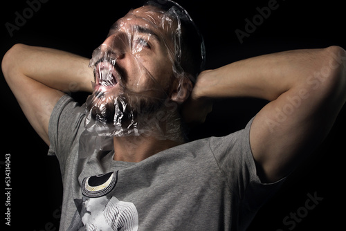 Fotografia Portrait of a guy with a plastic bag on his face on a black background