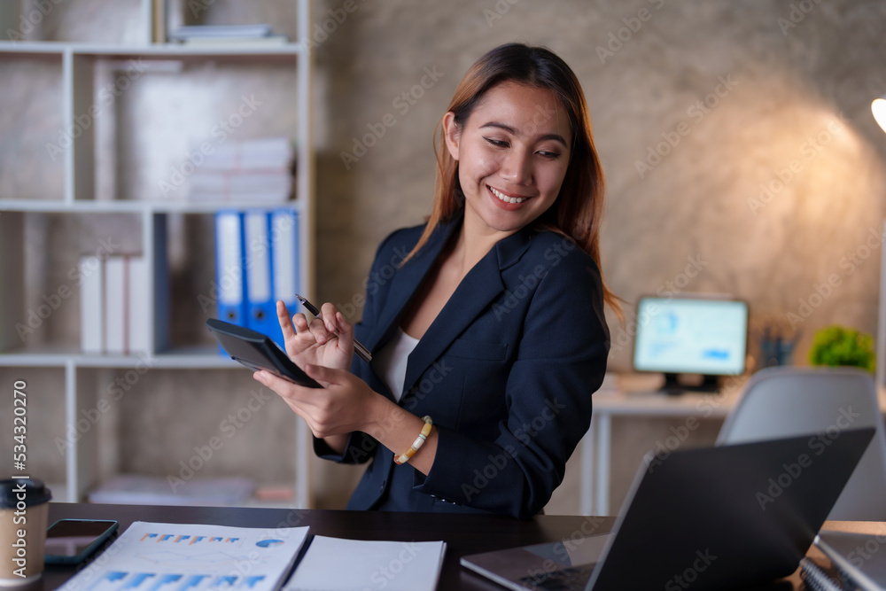 Happy Asian business woman using her laptop to work and enjoy working, taking note, reviewing assignment and smiling in the office. Happy Asian business woman using her laptop to work and enjoy working, taking note, reviewing assignment and smiling in the office.