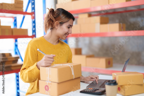 Young Asian online business owner woman is preparing a parcel box to prepare the package for delivery to the customer. Online SME business entrepreneur idea.