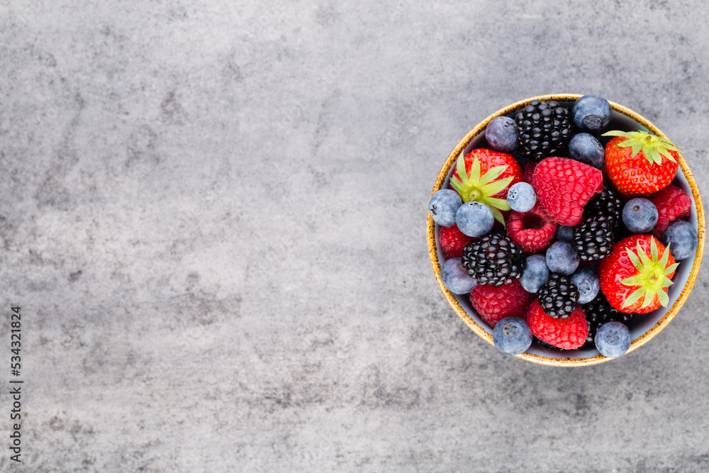 Fresh berry salad on blue dishes. Vintage wooden background.