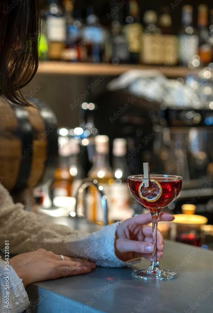 A girl drinks an alcoholic bellini cocktail at the bar. A girl sits at a bar