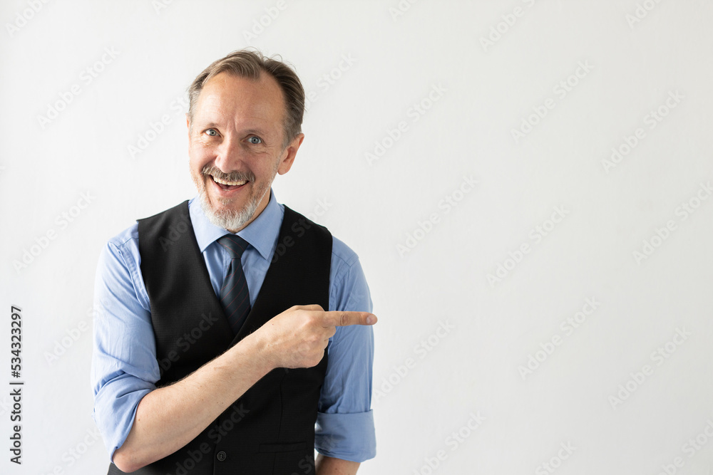 Portrait of cheerful mature businessman advertising something. Senior Caucasian manager wearing formalwear pointing finger and smiling against white background. Advertising concept Portrait of cheerful mature businessman advertising something. Senior Caucasian manager wearing formalwear pointing finger and smiling against white background. Advertising concept