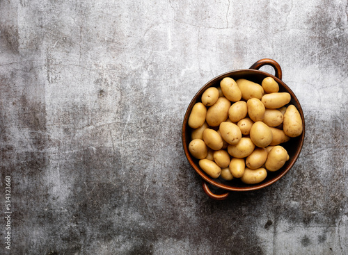 Raw small potatoes in a cast iron skillet on a beton background.