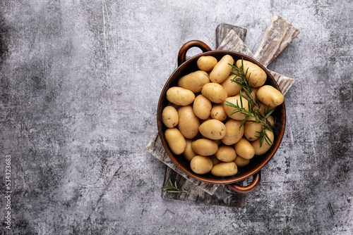 Raw small potatoes in a cast iron skillet on a beton background.