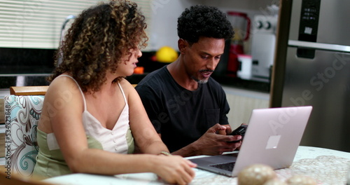 Candid black couple doing money budget together in front of computer laptop
