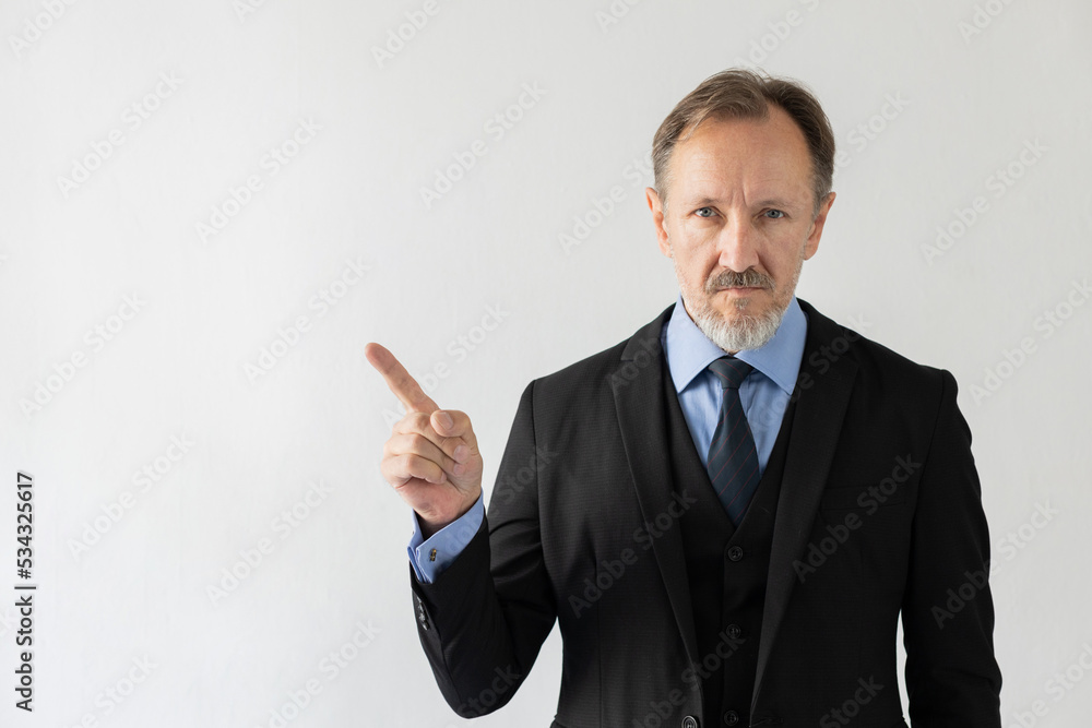 Portrait of serious mature businessman making attention gesture. Senior Caucasian sales manager wearing three piece suit having idea or pointing at something. Presentation and idea concept Portrait of serious mature businessman making attention gesture. Senior Caucasian sales manager wearing three piece suit having idea or pointing at something. Presentation and idea concept