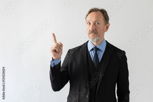 Portrait of surprised mature businessman getting solution. Senior Caucasian man wearing three piece suit looking at camera showing index finger. Idea, solution and business strategy concept