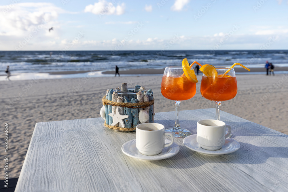 Beach cafe, two cups of coffee and drinks on the table. In the background the Baltic Sea and an empty beach, Island Wolin, Miedzyzdroje, Poland