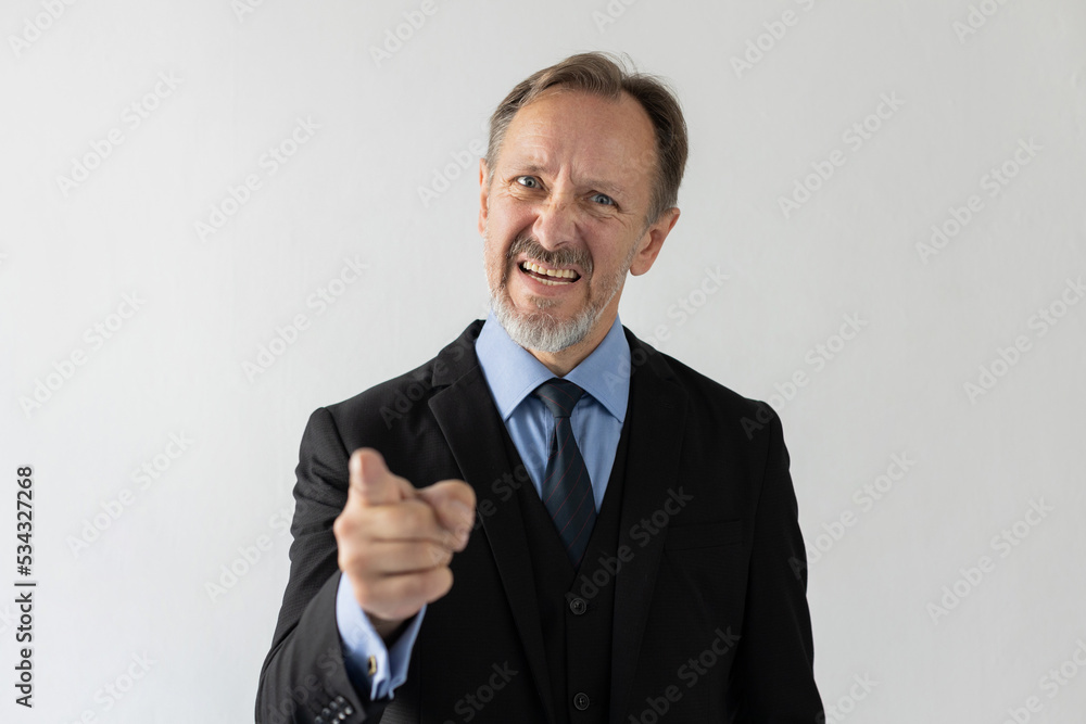 Portrait of angry mature businessman pointing at camera. Grumpy senior Caucasian manager wearing three piece suit scolding someone and looking at camera. Blame and angry boss concept Portrait of angry mature businessman pointing at camera. Grumpy senior Caucasian manager wearing three piece suit scolding someone and looking at camera. Blame and angry boss concept