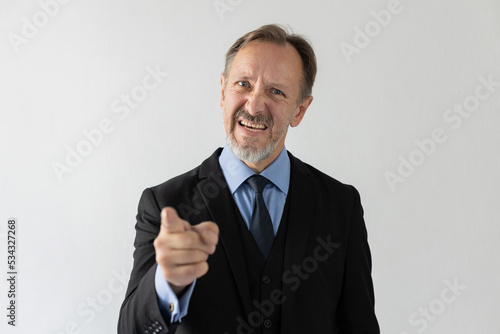 Portrait of angry mature businessman pointing at camera. Grumpy senior Caucasian manager wearing three piece suit scolding someone and looking at camera. Blame and angry boss concept