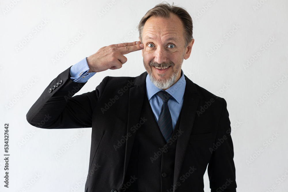 Portrait of smiling mature businessman making suicide gesture. Senior Caucasian manager wearing three piece suit making gun sign and looking at camera. Crisis and bankruptcy concept Portrait of smiling mature businessman making suicide gesture. Senior Caucasian manager wearing three piece suit making gun sign and looking at camera. Crisis and bankruptcy concept