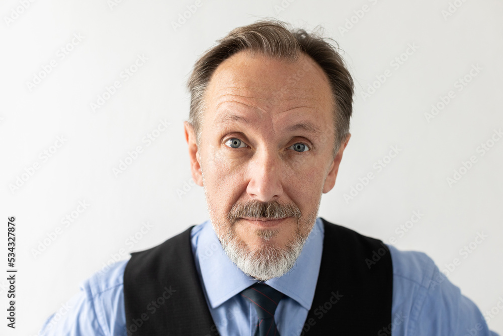 Close-up of confident mature businessman staring at camera. Portrait of bearded senior Caucasian manager wearing formalwear looking at camera against white background. Senior businessman concept Close-up of confident mature businessman staring at camera. Portrait of bearded senior Caucasian manager wearing formalwear looking at camera against white background. Senior businessman concept