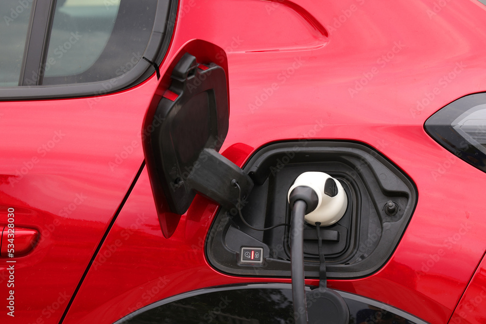 Charging cable and spot for an red car,electric vehicle. Green energy and zero emissions is the future for automotive industry. Charging cable and spot for an red car,electric vehicle. Green energy and zero emissions is the future for automotive industry.