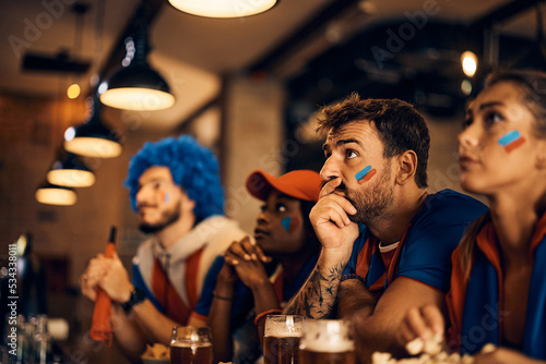Sports fan and his friends watching football match on TV during the world cup in bar.