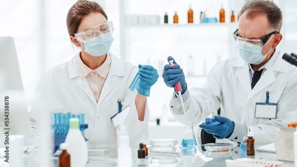 female scientist looks at the liquid in the test tubes . female scientist looks at the liquid in the test tubes .