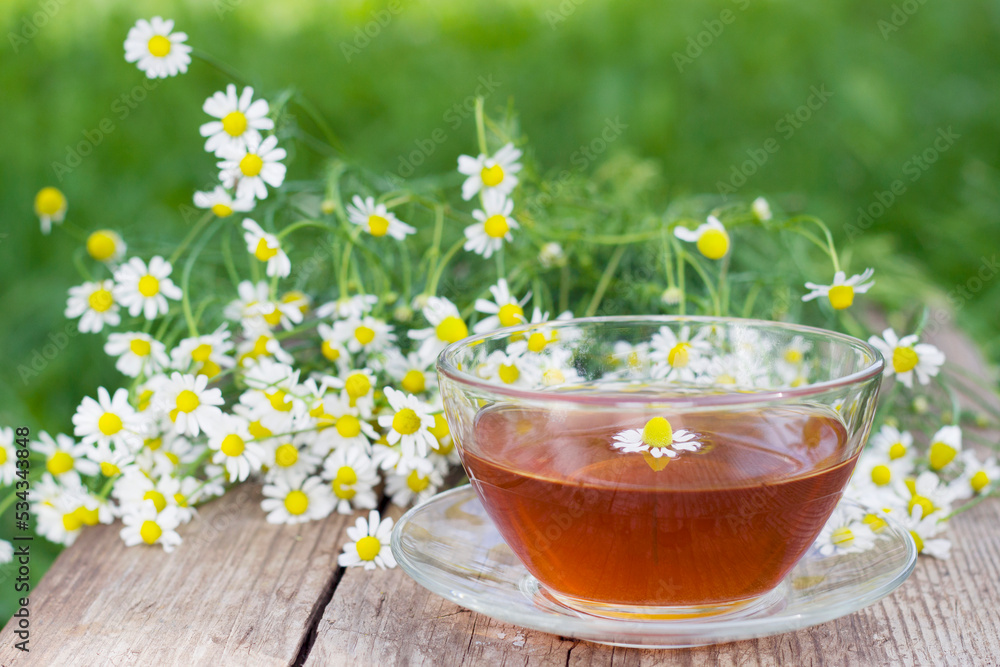 selective focus close up of herbal tea with chamomile on the wooden table with bouquet of flowers selective focus close up of herbal tea with chamomile on the wooden table with bouquet of flowers