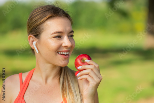 Active athletic sportive woman in sport outfit eating apple after the training