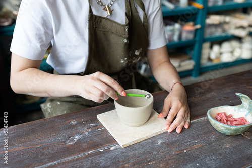 Woman doing pottery on the potter wheel on the workshop