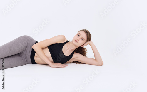 a beautiful woman in leggings and a top is lying on the floor resting after sports