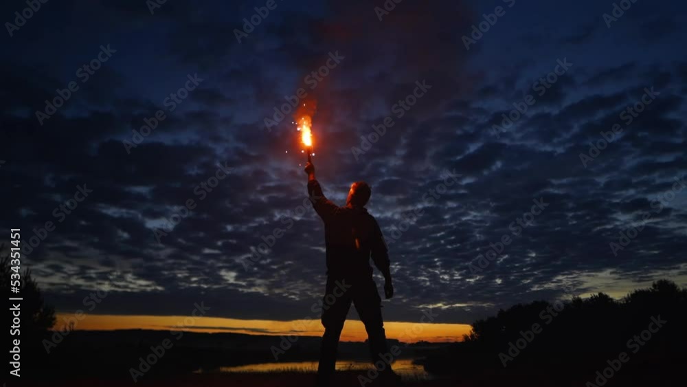 A lonely man with a red torch against the sunset A lonely man with a red torch against the sunset