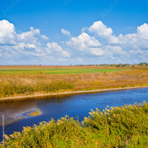 small quiet river among prairie under blue cloudy sky