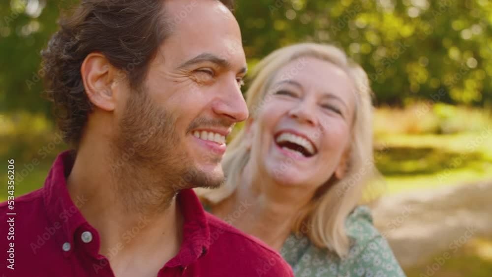Smiling mature parents with mixed race adult offspring leaning on wooden fence on walk in summer countryside talking together - shot in slow motion Smiling mature parents with mixed race adult offspring leaning on wooden fence on walk in summer countryside talking together - shot in slow motion