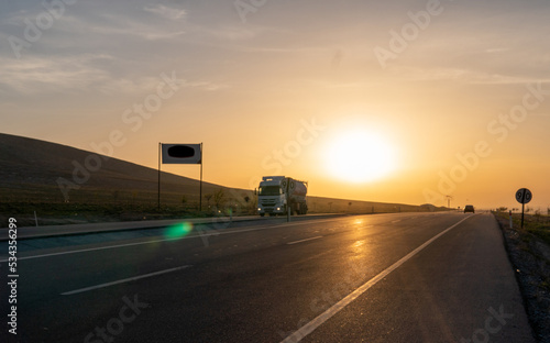 View of trucks carrying loads at sunrise